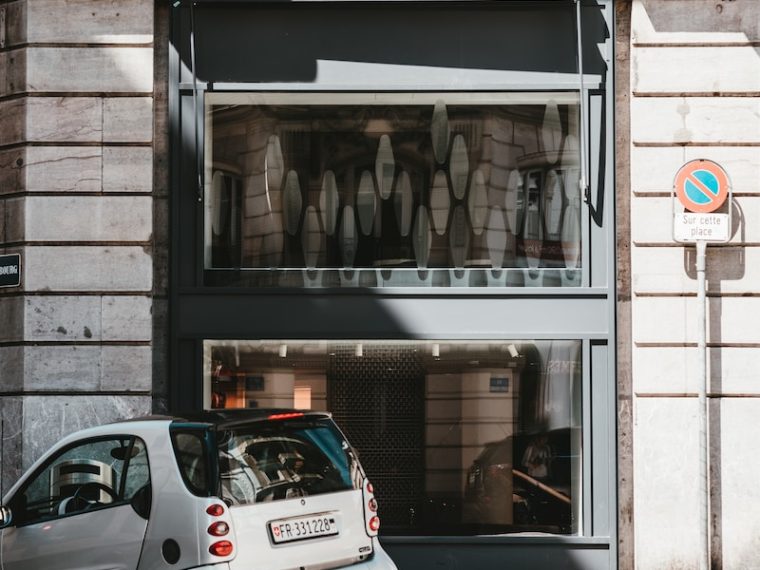 white 5 door hatchback parked beside brown brick building during daytime